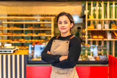 Dükkanda kolları çapraz duran Latin bir fırının gururlu kadın portresi.