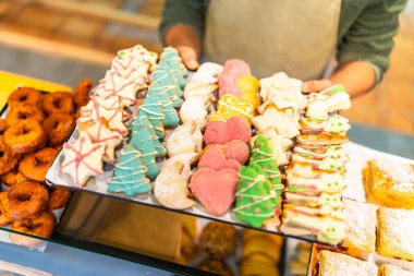 Dükkanda içinde Noel kurabiyeleri olan bir tepsi sunan bir erkek fırıncının yakın çekimi.