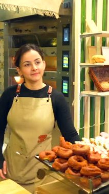 Latin genç bir adam modern bir pastaneden zanaatkar ekmeği alıyor arkadaş canlısı genç bir Latin kadının katılımıyla