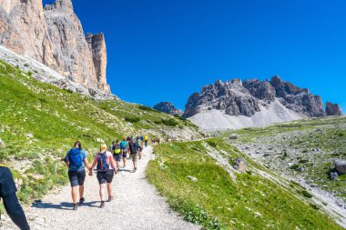 Turistler, yazın dolomitlerin nefes kesen dağ manzarasının ortasında Tre cime di lavaredo patikasında manzaralı bir yürüyüş yapıyorlar.