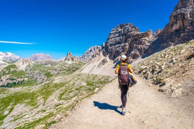 Güneşli bir yaz gününde arka planda Tre cime di lavaredo ile Dolomites dağlarında bir patikada yürüyen kadın yürüyüşçü.