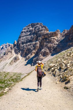 Sırt çantalı bir turist güneşli bir yaz gününde İtalyan dolomitleriyle Tre cime di lavaredo 'nun etrafında yürüyor.