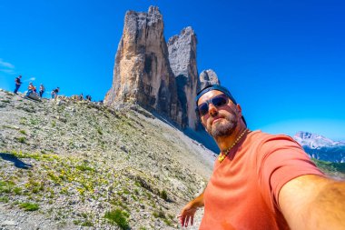 Dolomitler, İtalya 'da yaz boyunca arka planda Tre cime di lavaredo dağlarıyla selfie çeken bir turist.