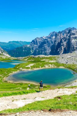 Turist, Tre cime di lavaredo 'nun nefes kesici manzarasının ve İtalyan dolomitlerindeki turkuaz gölün yaz boyunca fotoğraflarını çekiyor. Laghi dei Piani