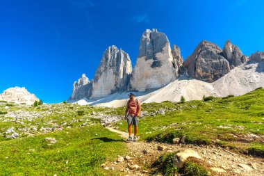 İtalyan dolomitlerinin göz kamaştırıcı dağ grubu olan tre cime di lavaredo 'nun eteklerinde yaz yürüyüşünün tadını çıkaran bir turist.