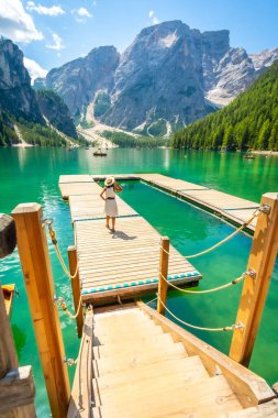 Braies Gölü 'ndeki ahşap bir iskelede yürüyen turist, Pragser Wildsee olarak da bilinir, arka planda, dolomitlerde, İtalya' da