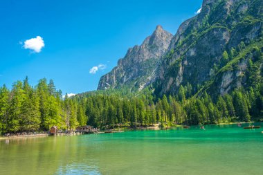 Güneşli bir yaz gününde arka planda dolomitlerle Braies Gölü 'nün zümrüt sularında kano yapan turistler.