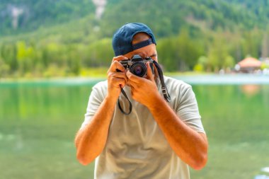 Turist, yaz tatili boyunca dolomitlerin nefes kesici manzarasıyla çevrili Dobbiaco Gölü 'ndeki manzaranın fotoğraflarını çekiyor.