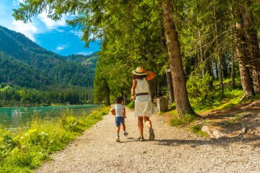 Anne ve oğlu Dobbiaco Gölü kıyısında güzel bir yaz gününde dolomitlerin sükunetinin tadını çıkarıyorlar.