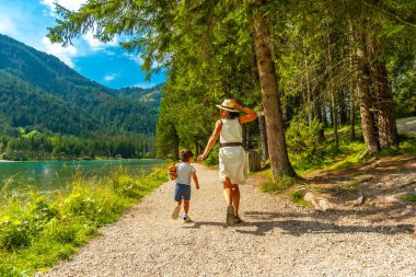 Anne ve oğlu Dobbiaco Gölü 'nün manzaralı kıyılarında yürüyüş yapıyorlar. Dolomitlerin yazın büyüleyici güzellikleriyle çevrili.
