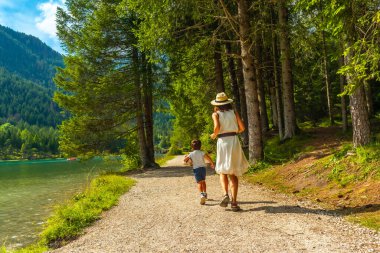 Turistler yazın büyüleyici dolomitlerle çevrili Dobbiaco Gölü 'nün manzaralı güzelliğinin tadını çıkarıyorlar.