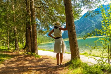 Dobbiaco Gölü kıyısında, dolomitlerin büyüleyici manzarasıyla çevrili bir kadın, İtalya