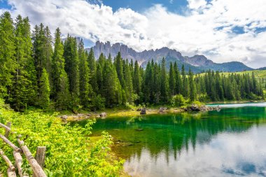 Zümrüt suları, güzel bir yaz gününde İtalyan dolomitlerindeki latemar sıradağlarını ve yemyeşil ormanları yansıtır.