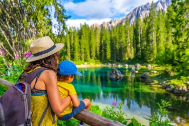 Turistler güzel bir yaz gününde İtalyan dolomitlerinde Carezza Gölü 'nün ve latemar Dağı' nın nefes kesici manzarasının keyfini çıkarıyorlar.