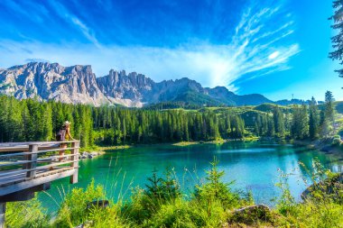 Carezza Gölü 'nün çarpıcı turkuaz sularına hayran kalan dişi turist arka planda gecikme sıradağları, dolomitler, İtalya