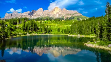 Güneşli bir yaz gününde Carezza Gölü 'nün zümrüt pürüzsüz sularını yansıtan latemar dağ grubunun çarpıcı manzarası, dolomitler, İtalyan Alpleri.