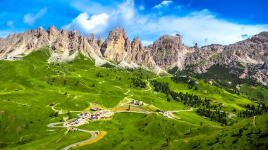 Görkemli dolomitlerin sardığı yemyeşil vadileri saran pitoresk gardenya geçidinin göz kamaştırıcı hava manzarası canlı mavi gökyüzünün altında.