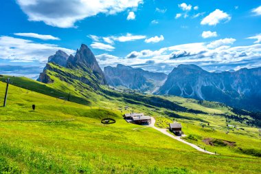 Güneşli bir yaz gününde İtalyan dolomitlerindeki seceda tepeleri ve yeşil çayırlar göz kamaştırıcı.