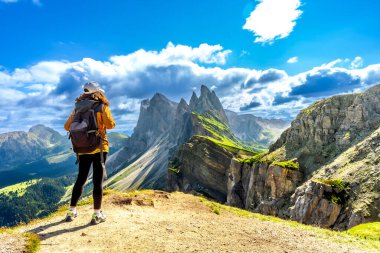 Sırt çantalı bayan turist güneşli bir yaz gününde İtalyan dolomitlerinin dağ sırasına hayran.