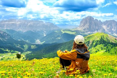 Yaz boyunca dolomitlerdeki seceda dağlarının göz kamaştırıcı manzarasının tadını çıkaran yürüyüşçü, renkli kır çiçekleriyle çevrili.