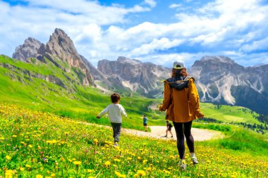 Turistler güneşli bir yaz gününün tadını çıkarıyorlar. Seceda 'daki kır çiçekleri, dolomitler ve İtalya' da geziniyorlar.