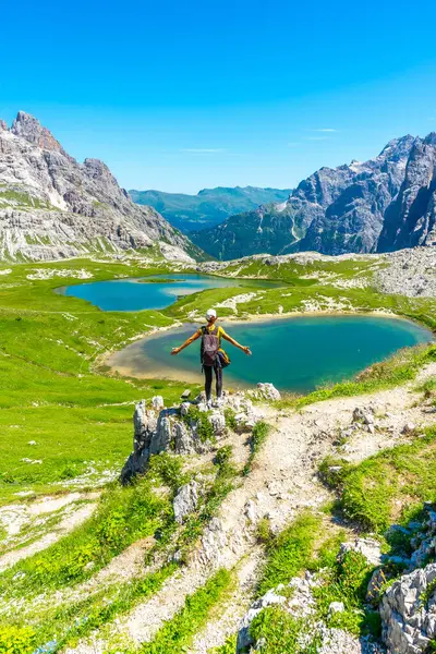 Kolları açık kadın yürüyüşçü İtalyan dolomitlerindeki tre cime di lavaredo ve alp göllerinin muhteşem manzarasının tadını çıkarıyor. Laghi dei Piani