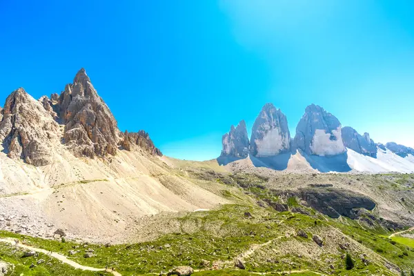 İtalyan dolomitlerinin güneşli yaz gününün tadını çıkaran yürüyüşçülerle birlikte Tre cime di lavaredo panoramik manzarası