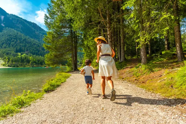 Anne ve oğlu Dobbiaco Gölü 'nün çakıl yolu boyunca koşuyor, dolomitlerde yaz tatilinin tadını çıkarıyorlar.