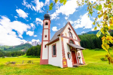 Büyüleyici St. Magdalena Kilisesi yeşil bir çayıra kurulmuş görkemli dağ ve yemyeşil ormanlarla çarpıcı bir zemin oluşturuyor.