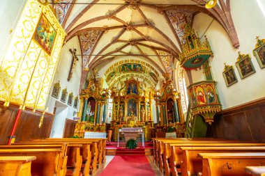 Zengin dekore edilmiş bir sunak, canlı freskler ve geleneksel ahşap kürsü ile St. Magdalena kilisesi Val di Funes, İtalya 'da sergileniyor.
