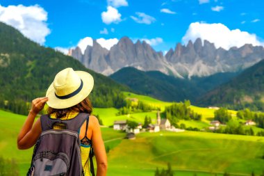Sırt çantalı kadın yürüyüşçü, St. Magdalena Kilisesi ve Odle Dağları 'nın bulunduğu Val di Funes vadisine hayran kaldı.