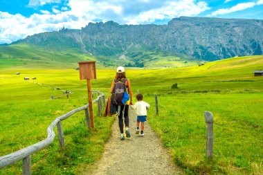 Turistler, İtalyan dolomitlerinin çarpıcı dağ manzarasıyla çevrili güzel Alpe di Siusi 'de manzaralı bir yürüyüş yapıyorlar.