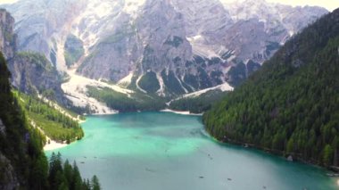 Turkuaz su ve yemyeşil ormanlar, dolomitlerde güzel bir yaz günü kayak yapan turistlerle gölün etrafını sarar.