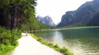 Anne ve oğlu Dobbiaco Gölü 'nün çakıl yolu boyunca koşuyor, dolomitlerde yaz tatilinin tadını çıkarıyorlar.