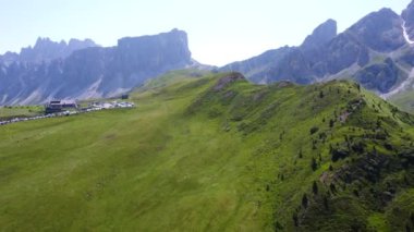 İtalyan dolomitlerindeki berrak mavi gökyüzünün altındaki canlı yeşil dağların arasından geçen yürüyüş yolunun manzarası.