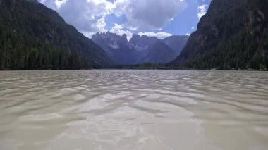 Turistler, güneşli bir yaz gününde dolomitlerin nefes kesici zirveleriyle çevrili lago di landro 'nun turkuaz sularında yüzüyor ve kürek çekiyorlar.
