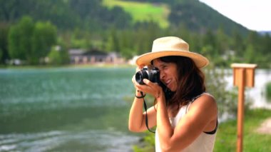 Turist, İtalyan dolomitlerindeki Dobbiaco Gölü 'ndeki güzel manzaranın klasik fotoğraf makinesiyle yaz tatillerinde fotoğraf çekiyor.