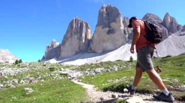 Turist, yazın dolomitlerin nefes kesen zirveleri arasında Tre cime di lavaredo patikasında manzaralı bir yürüyüş yapıyor.