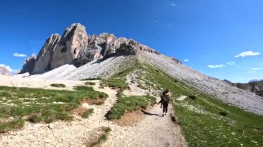 Güneşli bir yaz gününde İtalyan dolomitlerindeki Tre cime di lavaredo zirvelerini nefes kesen bir dağ yolunda yürüyüş yapan kadın turist.