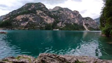 Dolomitlerin zümrüt suları, turistlerin kayak yaptığı, çam ağaçlarının canlı yeşil dalları tarafından çerçevelenmiş.