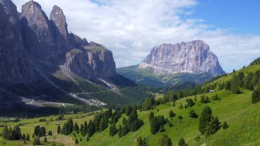 Görkemli tepeler ve yemyeşil çayırlar güneşli bir yaz günü İtalyan dolomitlerinin kalbinde güneşli bir bahçe geçidi boyunca çarpıcı bir manzara yaratır.