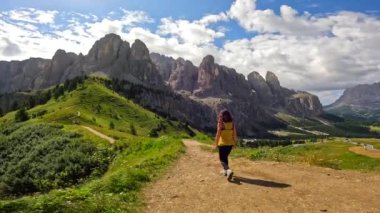 Bir dağ yolunda yürüyen yürüyüşçü yaz boyunca İtalyan Alplerinde dolomitlerin nefes kesici manzarasının tadını çıkarıyor.