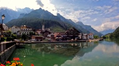 Turistler, güzel bir yaz gününde büyüleyici dolomitlerin içinde alegori gölünün resimli kıyılarında gezinerek doğanın güzelliğinin tadını çıkarıyorlar.