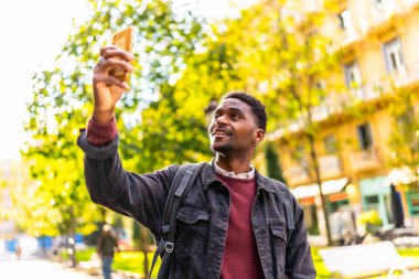 Afrikalı genç bir gezgin cadde boyunca yürürken bir şehrin fotoğraflarını çekiyor.