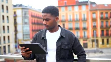 Sıradan bir Afrikalı adam şehirde dijital tablet kullanırken yukarı bakıyor.