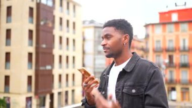 Afrikalı bir adam şehirdeki cep telefonunu kullanarak sesli mesaj gönderiyor.