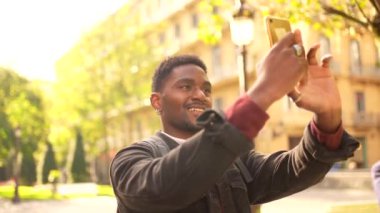 Afrikalı genç bir gezgin cadde boyunca yürürken bir şehrin fotoğraflarını çekiyor.