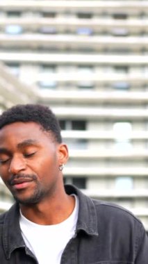 Afrikalı bir vlogger şehirde video blogu kaydederken kameraya el sallıyor