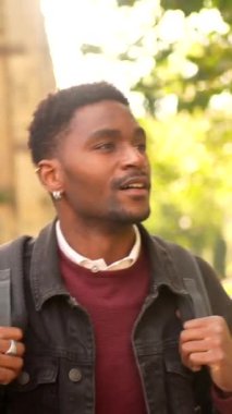 Afrikalı bir adam bir şehirde yürürken gülümsüyor.