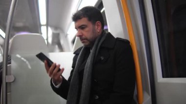 Yakışıklı, beyaz iş adamı. Metroda oturan cep telefonuyla konuşurken pencereden bakıyor.